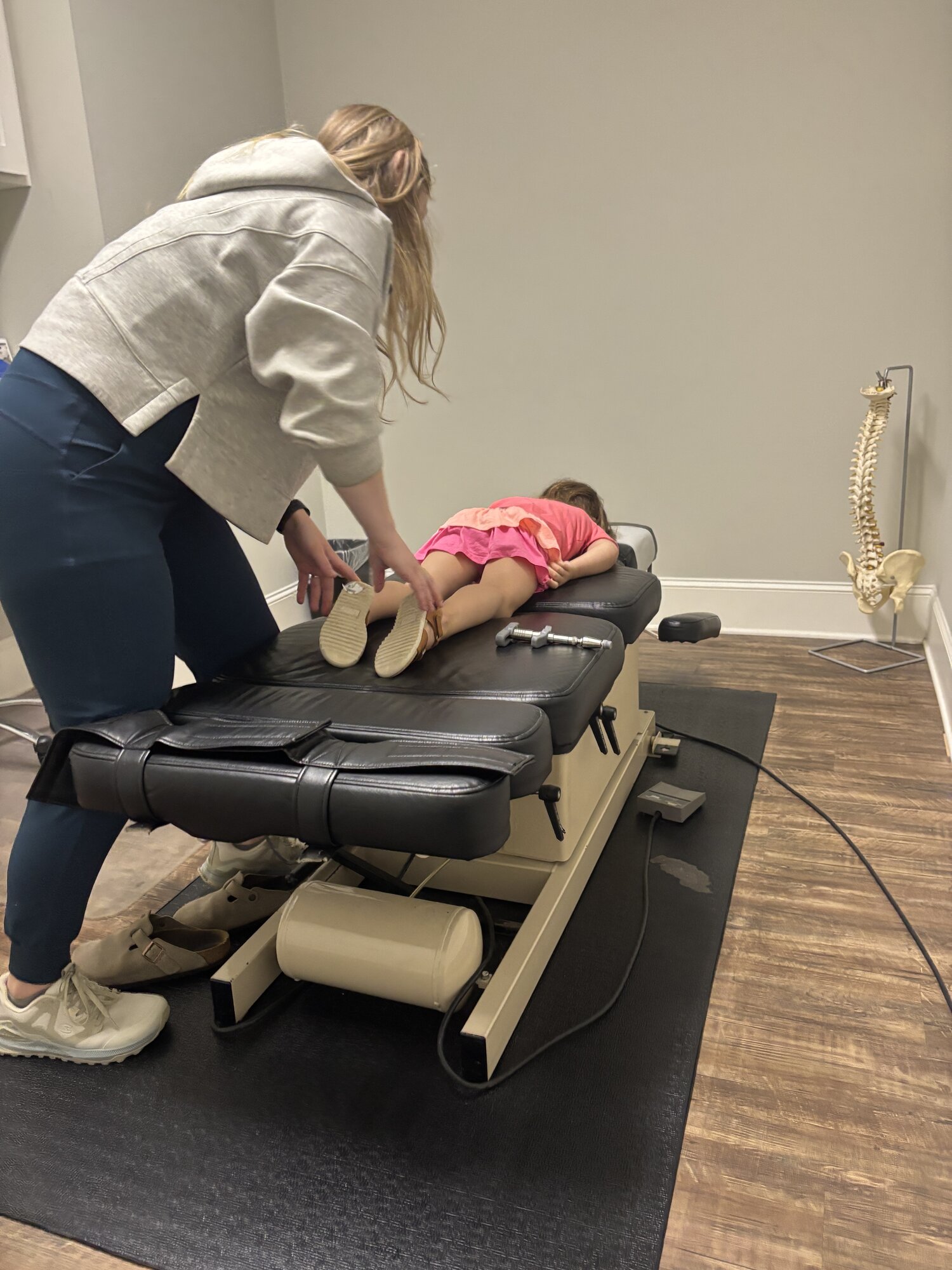 Dr. Corie Terwilliger working with a small child on the treatment table, providing age-appropriate care alongside the spinal anatomy model
