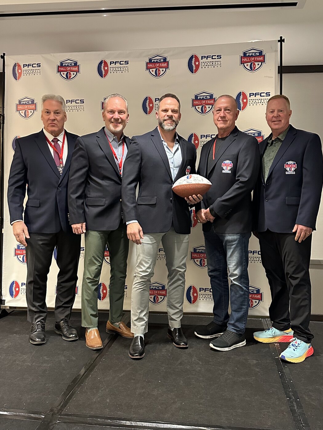 Dr. Joseph Krzemien (center) with fellow 2025 inductees of the Professional Football Chiropractic Society Hall of Fame, on the PFCS step-and-repeat