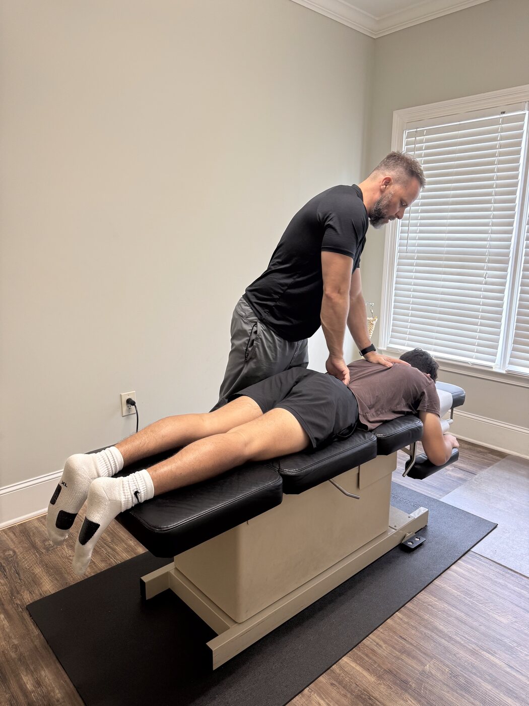 Dr. Joe Krzemien working with a male patient in the adjustment room, full view of the treatment space