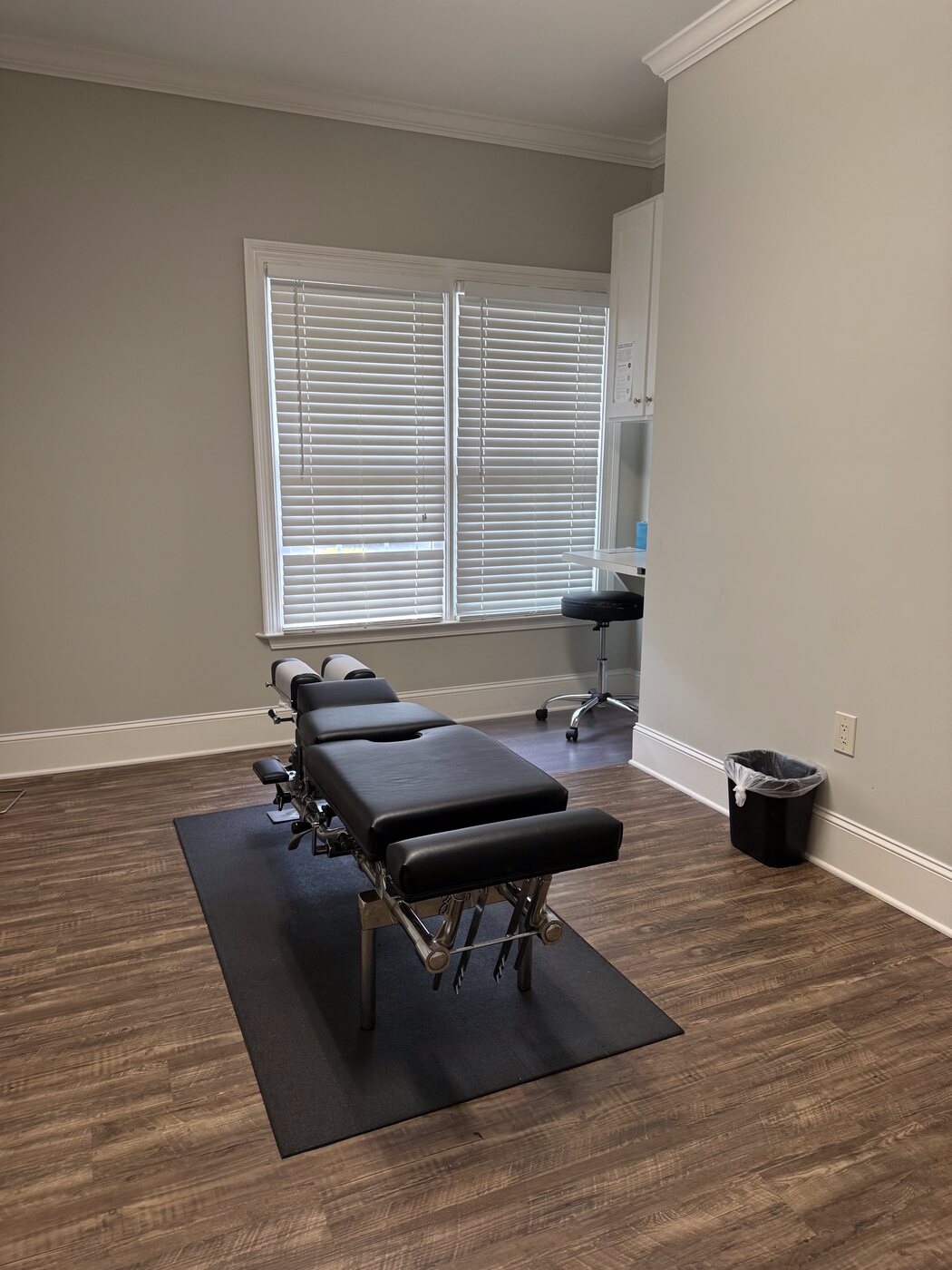 A clean treatment room at Georgia Spine and Sports Rehab with the adjustment table centered, window light, and minimal styling
