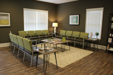 The waiting room at Georgia Spine and Sports Rehab, with green upholstered chairs and warm wood floors